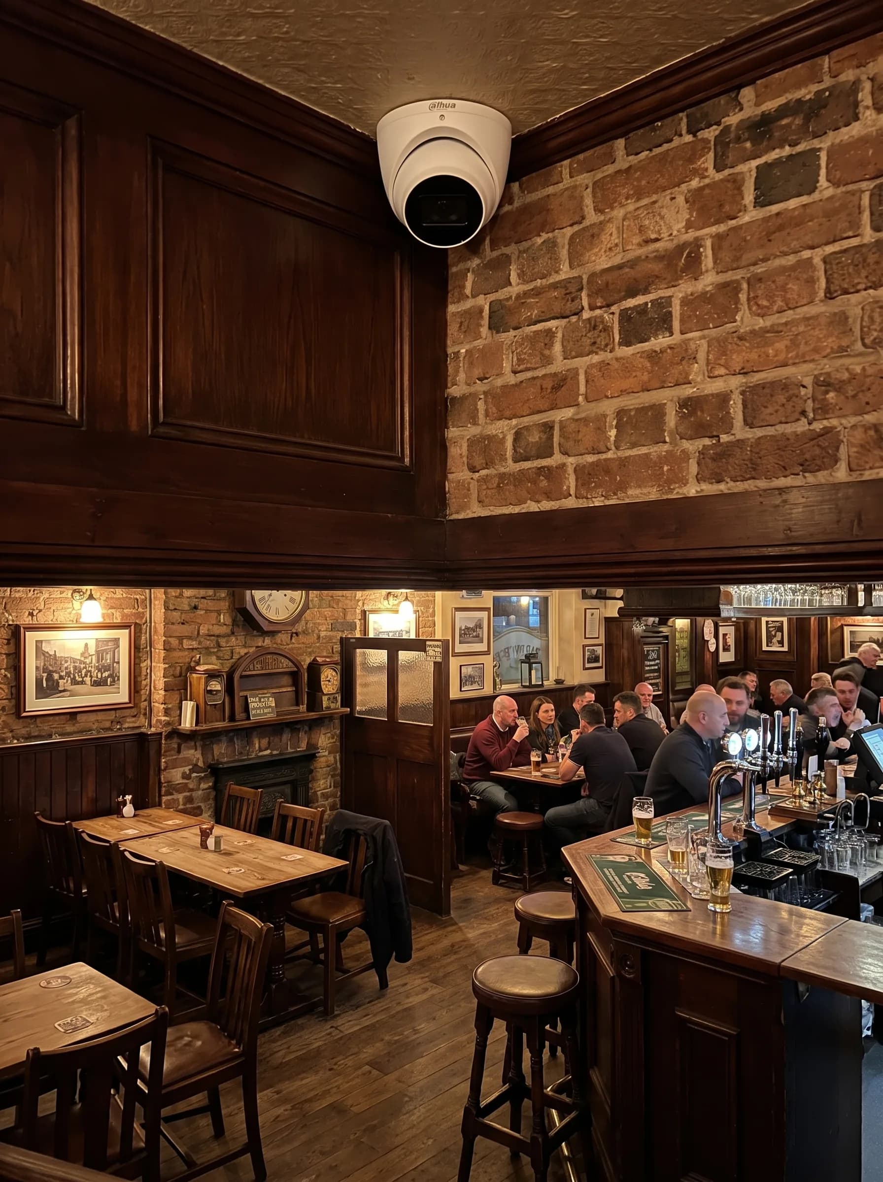 Dome CCTV camera fitted high on the wall of a busy pub