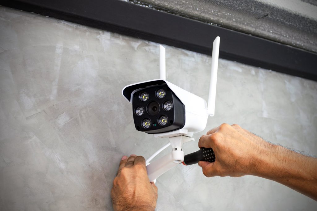 Technician installing wireless CCTV camera on wall
